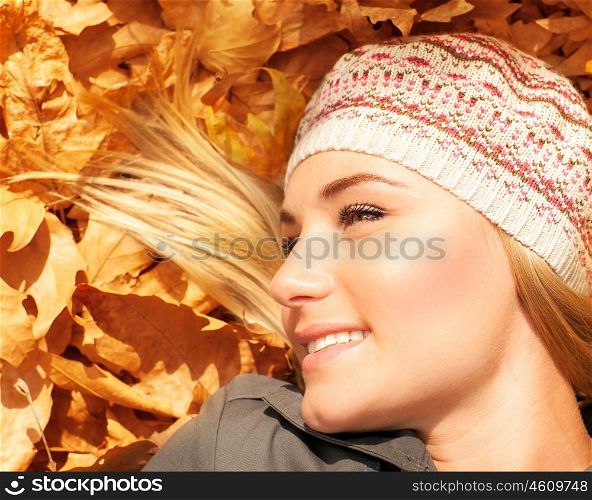 Photo of cute young lady laying down on the ground in autumn park, cute blond teenager having fun outdoors, having fun, rest outdoor, pleasure expression, fall season, freedom and carefree concept&#xA;
