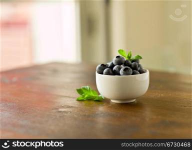 photo of delicious blueberries with mint leaf on wooden table