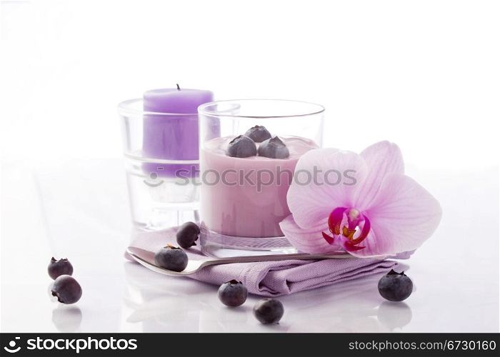 photo of delicious blueberry yoghurt with orchid and candle