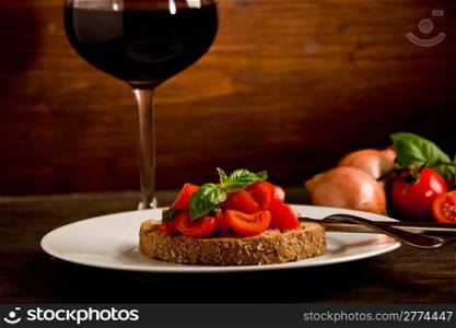 photo of delicious bruschetta appetizer with red wine glass on wooden table