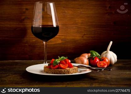photo of delicious bruschetta appetizer with red wine glass on wooden table