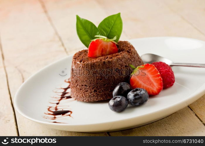 photo of delicious chocolate dessert with berries on wooden table