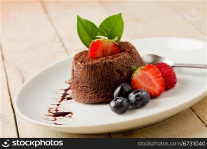 photo of delicious chocolate dessert with berries on wooden table