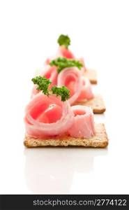 photo of delicious crackers with ham and parsley on white background