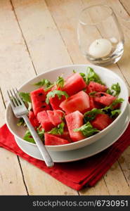 photo of delicious fresh watermelon and arugula salad on wooden table