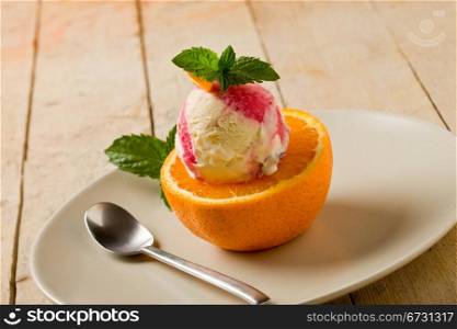 photo of delicious fruity ice cream on cutted orang with fresh mint leaves