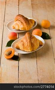 photo of delicious golden croissants with apricot marmalade on wooden table