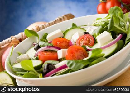 photo of delicious greek salad on wooden table in front of blue background with spot light
