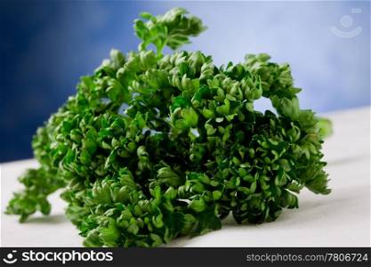 photo of delicious green and fresh parsley on white towel in front of blue background
