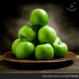 photo of delicious green apple inside a basket on wooden table