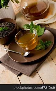 photo of delicious green mint tea in glass cup on wooden table