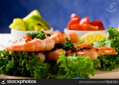 photo of delicious grilled prawns over lettuce bed with peperoni over blue background
