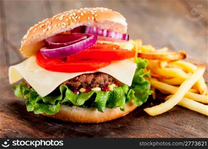 photo of delicious hamburger with fries on wooden table