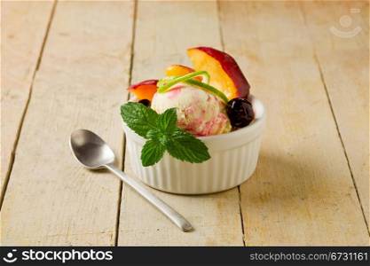 photo of delicious ice cream with fruits inside a cup on wooden table