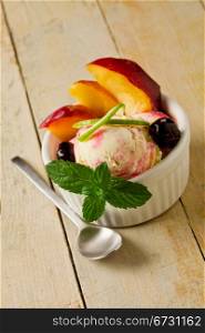 photo of delicious ice cream with fruits inside a cup on wooden table