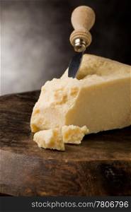 photo of delicious italian parmesan cheese with knife on wooden table