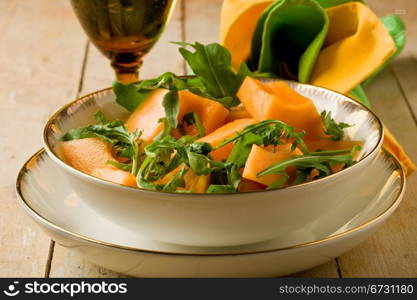 photo of delicious melon and arugula salad on wooden table