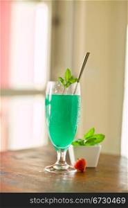 photo of delicious mint cocktail on wooden table illuminated by daylight