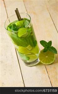 photo of delicious mojito cocktail with cuttd lime on wooden table
