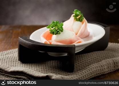 photo of delicious mozzarella with wrapped ham on wooden table