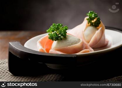 photo of delicious mozzarella with wrapped ham on wooden table