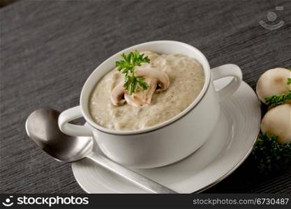 photo of delicious mushroom cream soup with parsley on grey towel