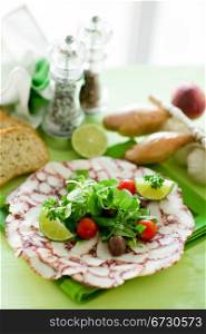 photo of delicious octopus carpaccio with mixed salad illuminated by daylight