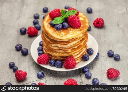 Photo of delicious pancakes with berries over wooden table