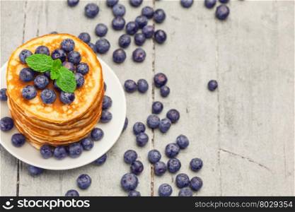 Photo of delicious pancakes with blueberries over wooden table