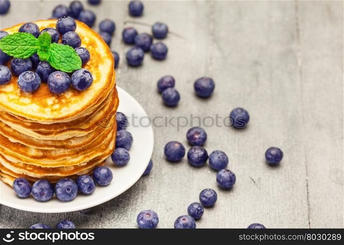 Photo of delicious pancakes with blueberries over wooden table