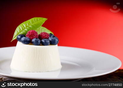 photo of delicious panna cotta with berries on red background