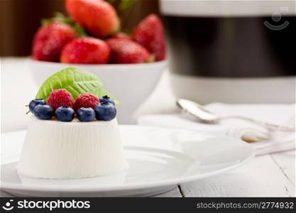 photo of delicious panna cotta with berries on white wooden table