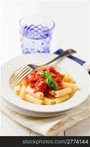 photo of delicious pasta with basil and tomato sauce on white wooden table
