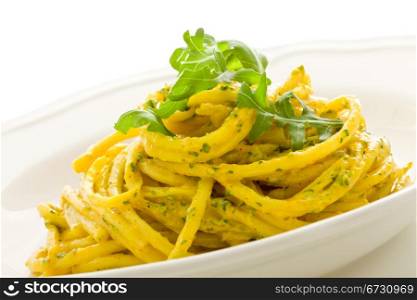 photo of delicious pasta with saffron and arugula pesto on isolated background