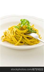 photo of delicious pasta with saffron and arugula pesto on isolated background