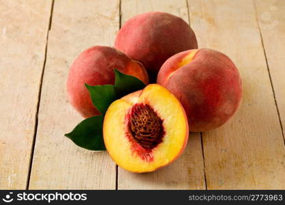 photo of delicious peaches on wooden table with leaves