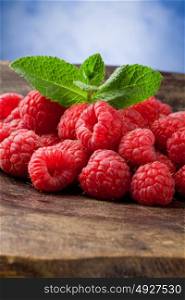 photo of delicious red raspberries with mint leaves on wooden table