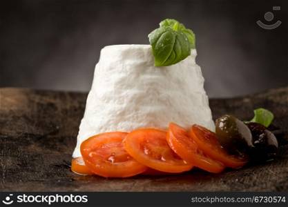 photo of delicious ricotta cheese with tomatoes on wooden table with basil