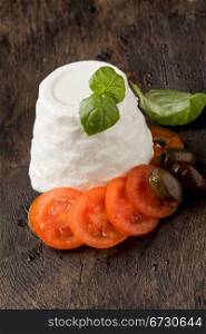 photo of delicious ricotta cheese with tomatoes on wooden table with basil