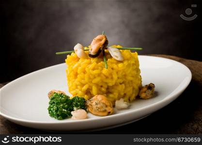 photo of delicious risotto with saffron and seafood on wooden table