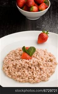 photo of delicious risotto with strawberries and champagne on black table