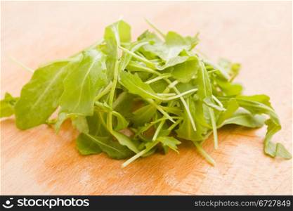 photo of delicious rocket salad on wooden cutting board