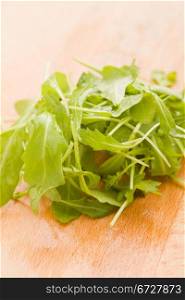 photo of delicious rocket salad on wooden cutting board
