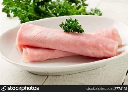 photo of delicious rolled ham with parsley on wooden table