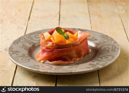 photo of delicious sliced bacon with melon inside on wooden table