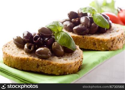 photo of delicious sliced bread with olives and basil