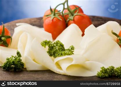 photo of delicious sliced cheese plate with tomatoes and parsley