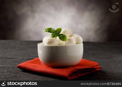photo of delicious small mozzarella cherries with basil inside a bowl