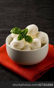 photo of delicious small mozzarella cherries with basil inside a bowl