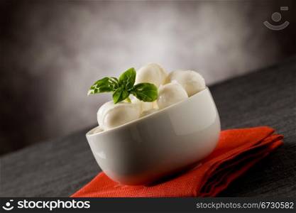 photo of delicious small mozzarella cherries with basil inside a bowl